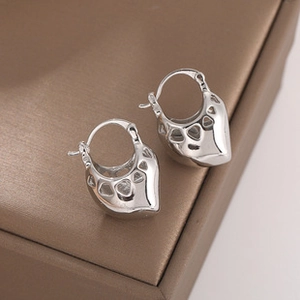 Close-up of silver mesh hollow heart earrings on a minimalist brown jewelry box