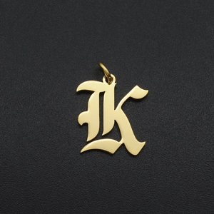 Gothic font letter K gold pendant accessory shown on a dark textured background