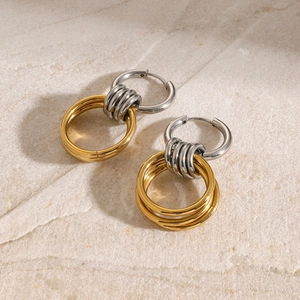 Two-tone 18K gold and silver intertwined hoop earrings on a marble stone surface