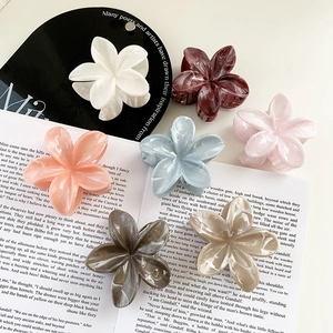 Floral hair claws in creamy colors and marble texture displayed on an open book