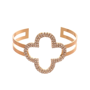 Bracciale aperto in oro con quadrifoglio traforato e strass per donna su sfondo bianco