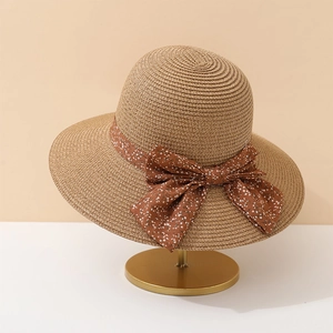 Détail d'un chapeau de paille kaki avec ruban à fleurs marron sur support doré