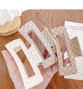 Detailed close-up of quilted pattern hair claws in cream, beige, and camel colors
