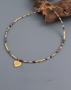 Detail of colorful tourmaline beads and golden heart pendant with engraved eye motif