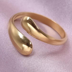Macro shot of minimalist adjustable gold rings on soft purple silk fabric background