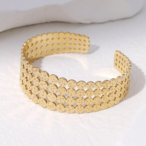 Macro detail of gold-plated stainless steel cuff with geometric hollow patterns