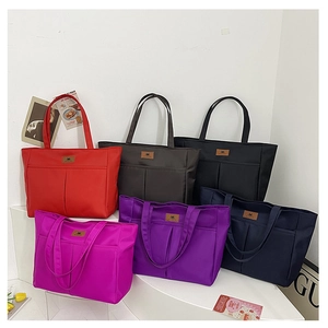 Detailed display of colorful nylon tote bags with double front pockets and leather labels