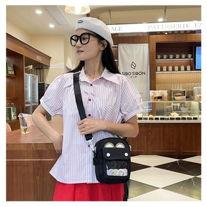 Close-up of black canvas crossbody bag with transparent window for anime badges