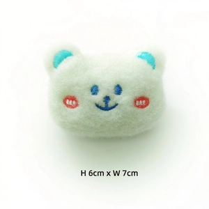 Detailed view of plush white bear pin with embroidery and 6cm by 7cm size dimensions
