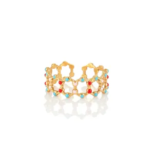 Macro detail of gold-plated honeycomb ring with colorful enamel inlay on white background