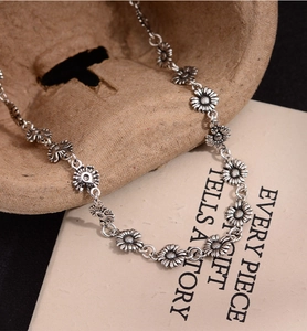 Macro detail of retro silver daisy necklace showing intricate flower relief and texture