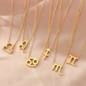 Golden zodiac necklaces collection featuring Libra, Leo, and Cancer pendants on satin