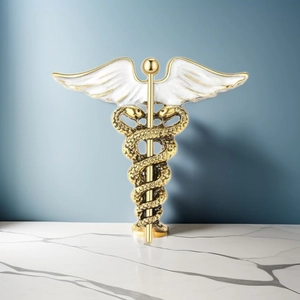 Macro detail of a golden caduceus brooch with white wings on a marble surface