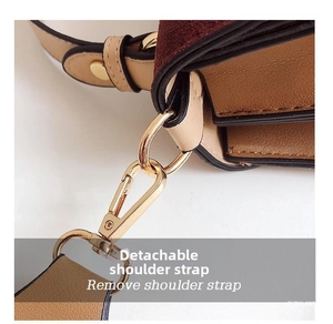 Detail of golden metal lobster clasp and suede leather stitching on crossbody bag