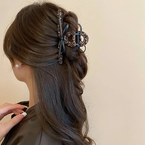 Detail view of a leopard print bow hair claw clip securing a chic half-up hairstyle