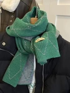 Detail of green and gray checkered knit scarf with a handmade label on a model