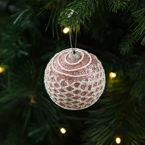 Pink rose gold Christmas ball ornament with glitter and white mesh on a festive tree