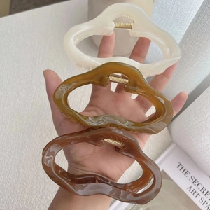 Three oversized glossy hair claws in cream, golden brown, and dark brown colors