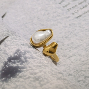 Polished gold open ring featuring a baroque pearl and geometric accent on a gray background