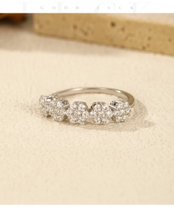 Macro shot of silver ring featuring five sparkling zircon flowers on a textured stone base