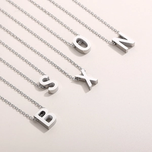 Detail of five polished silver initial pendants S O N X B on delicate chain necklaces
