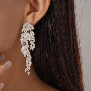 Silver vintage leaf tassel earrings with sparkling rhinestones worn on a model's ear