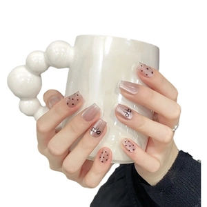 French press-on nails with black polka dots and butterfly crystals on nude base