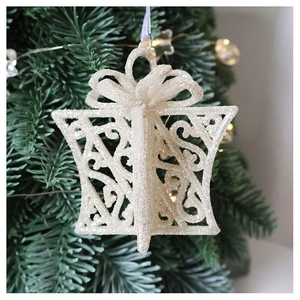 Detailed view of a glittering champagne gift box ornament hanging on a Christmas tree