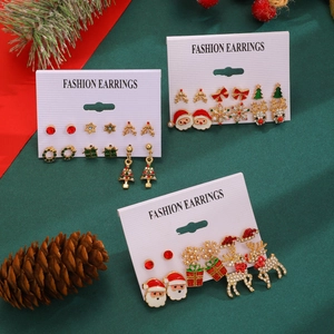 Macro detail of Christmas earring set with Santa, reindeer and tree on festive background