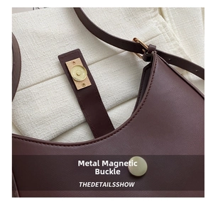 Détail du fermoir magnétique doré sur le sac à bandoulière en cuir marron foncé