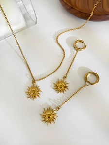 Detail of 18K gold-plated sun pendant necklace and earrings set on a clean background