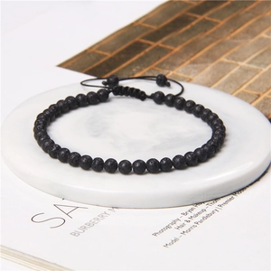 Macro detail of 4mm matte black lava stone beads on adjustable hand-woven braided bracelet