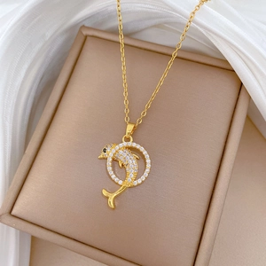 Detailed close-up of golden dolphin pendant with sparkling crystals in a jewelry box