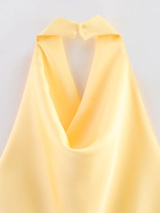 Détail du col d'un haut dos nu en satin jaune vif avec une texture de tissu lisse