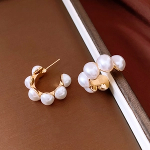Gros plan de boucles d'oreilles ovales en C dorées 18K avec perles blanches élégantes