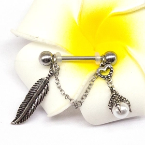 Detailed close-up of a vintage steel nipple ring with feather and pearl charm pendants