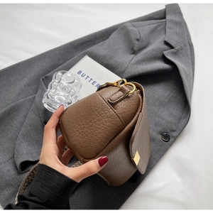 Détail du sac en cuir marron grainé avec boucle dorée et bandoulière tissée jacquard