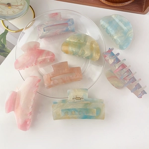Collection of colorful resin hair claws in pink and blue tones on a white background