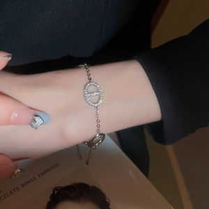 Close-up of a silver-tone zircon pavé anchor chain bracelet on a model wrist