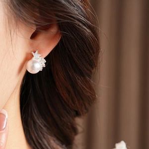 Détail d'une boucle d'oreille étoile et perle sur un mannequin avec des pierres de zircon