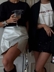 Dettaglio di t-shirt con stampa abbinate a gonne argentate con paillettes e spacco