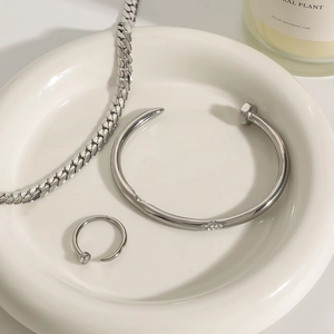 Minimalist silver steel bracelet and ring set displayed on a white ceramic tray