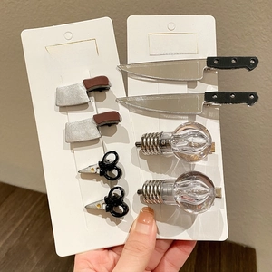 Detail of creative mini knife and light bulb hair clips set on a white card display