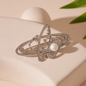 Detailed macro shot of a metallic planet brooch with white pearl and micro zircon inlays