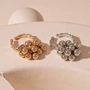 Irregular gold and silver clustered ball open rings on a minimalist stone pedestal