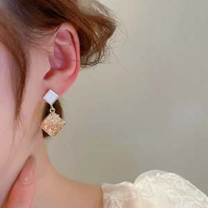 Detail of geometric rhinestone earrings with champagne gold diamond texture