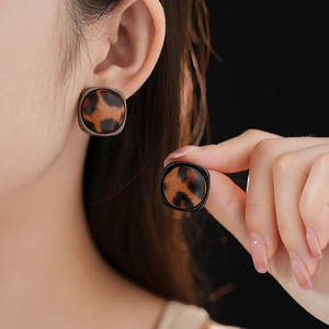 Gros plan des boucles d'oreilles léopard carrées avec cadre en métal et texture