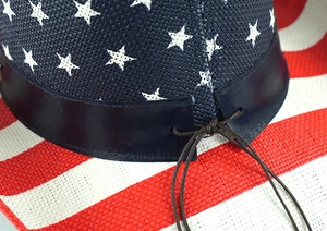 Détail du chapeau de paille western avec bande en cuir étoilée et texture tissée