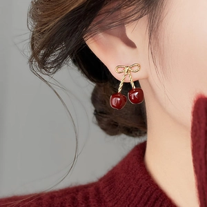 Macro shot of sweet cherry earrings with red resin fruits and golden bow details