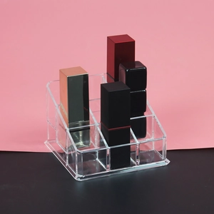 Close-up of a clear acrylic multi-grid lipstick organizer on a pink and black background